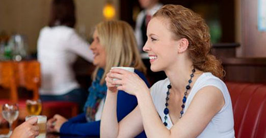 mujer sonriente tomando algo en una cafetería