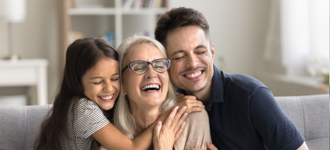Familia de abuela, padre e hija abrazándose felices mientras están sentados en el sofá