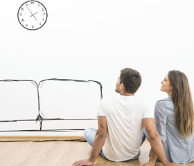 Pareja sentada en el suelo mientras se imaginan muebles de su casa