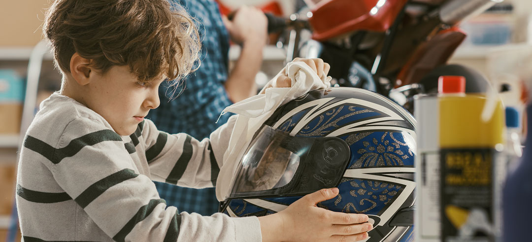 Niño limpiando el casco de una moto